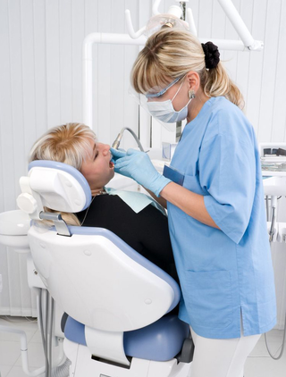a dental hydienist cleans the teeth of a dental patient