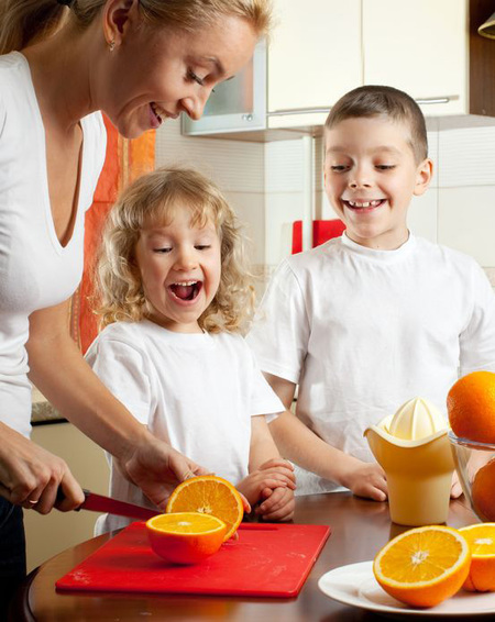 a mother slices oranges for her son and daughter